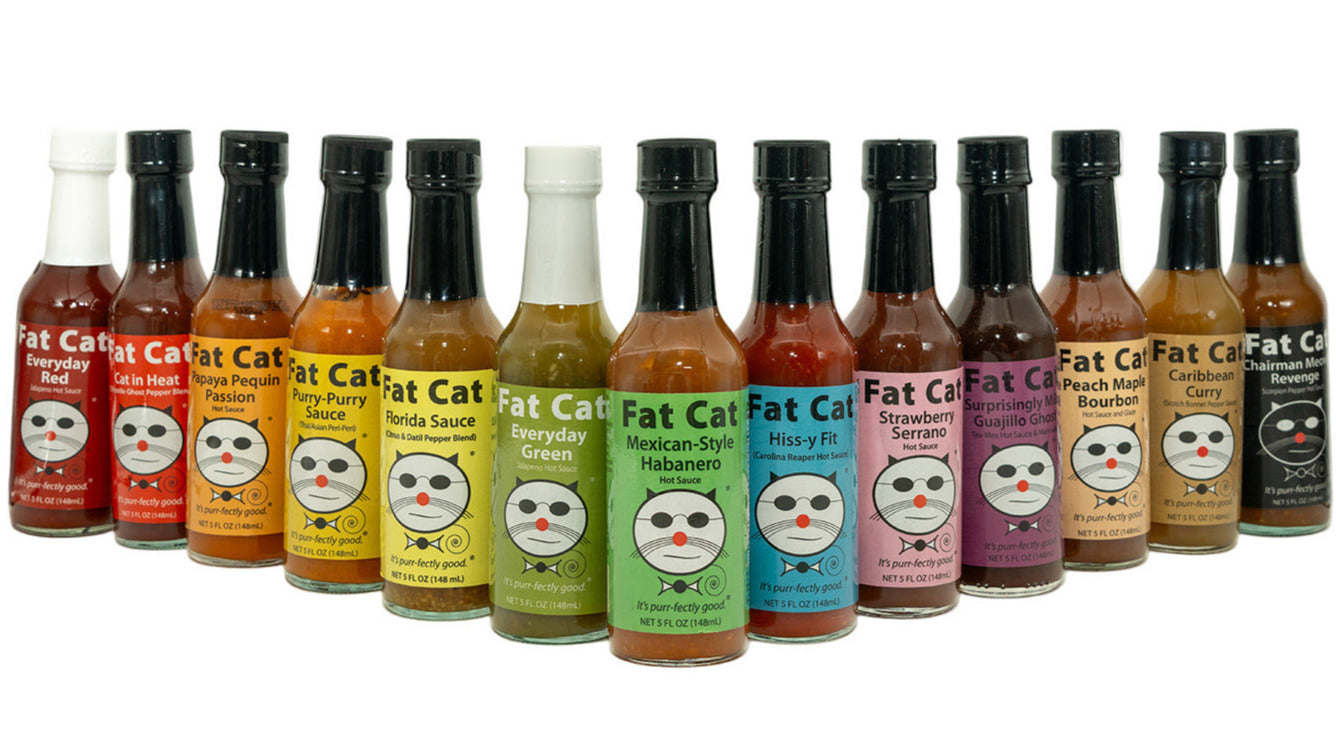 Row of Fat Cat hot sauce bottles with colorful labels on a white background